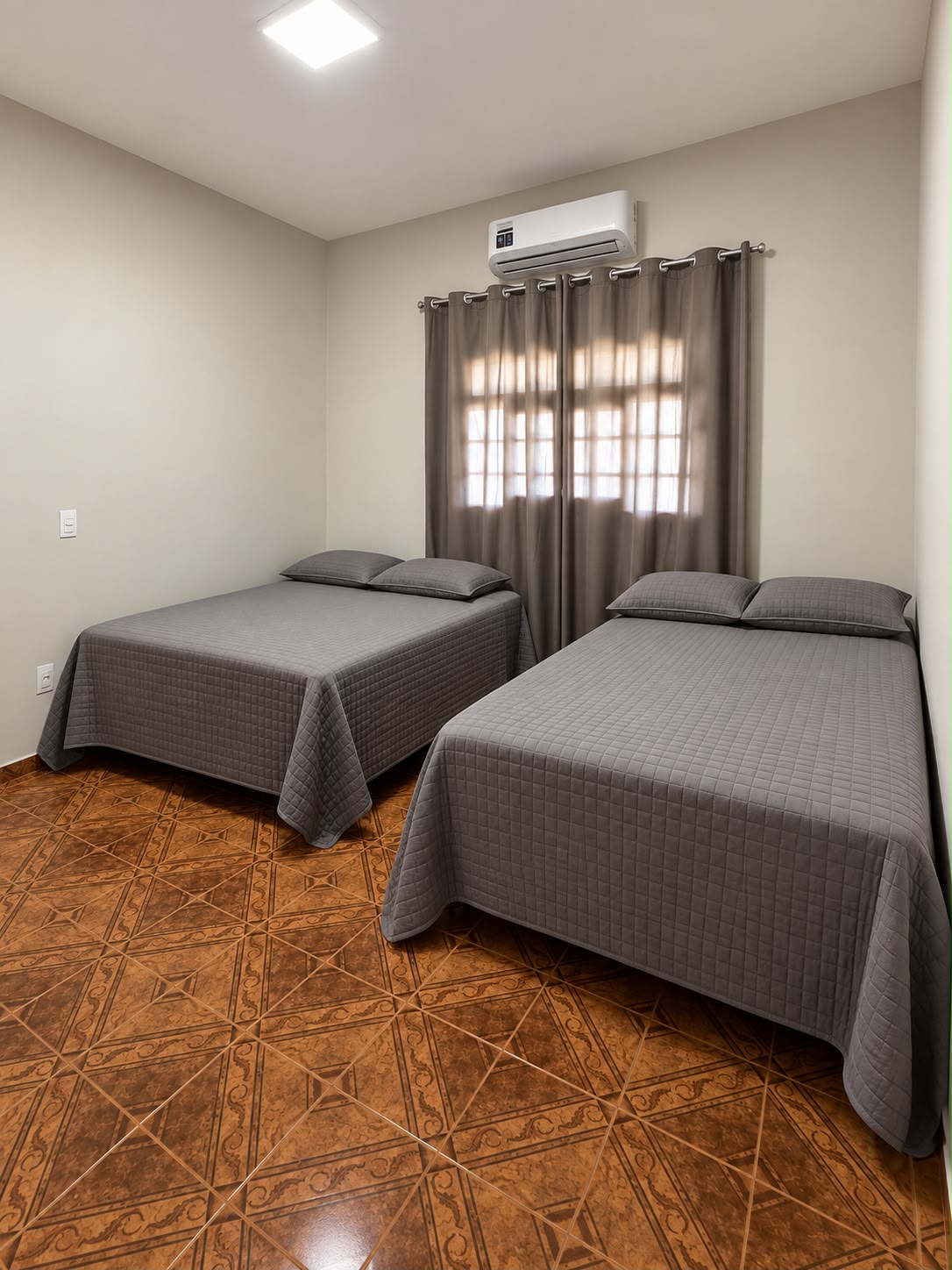 Quarto com duas camas de casal e roupa cinza